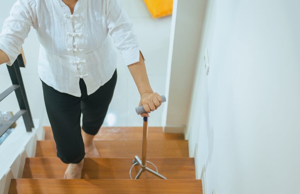 elderly woman walking up the stairs with walking cane