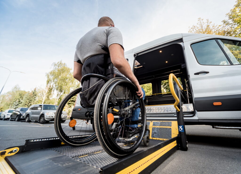 A man in a wheelchair moves to the lift of a specialized vehicle