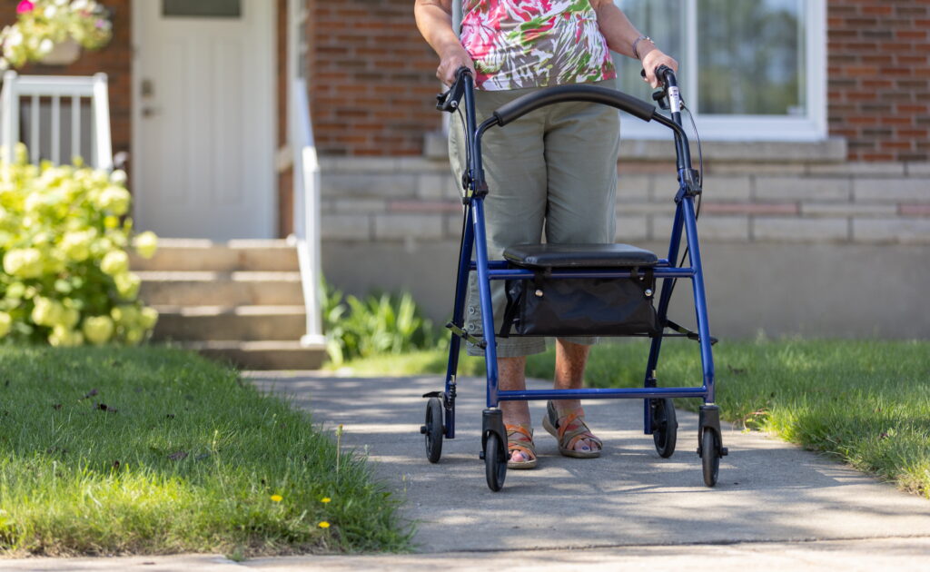 AdobeStock_525953209 Old woman walking outside with a rollator