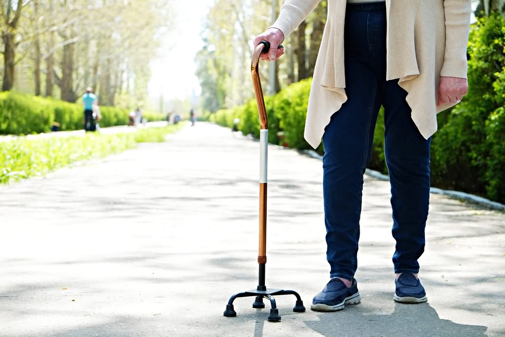 AdobeStock_272803392 elderly lady holding a walking stick outdoors